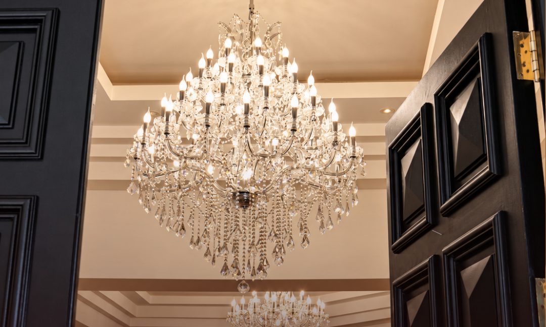Grand crystal chandelier in an entrance foyer seen through open front doors